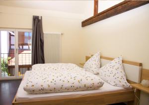 a bedroom with a bed with white sheets and pillows at Ferienhaus & Weingut am Steingebiss in Billigheim-Ingenheim