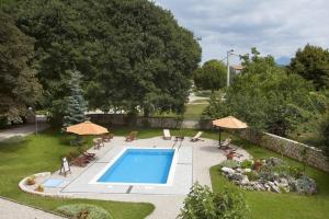 a swimming pool in a yard with chairs and umbrellas at Family friendly apartments with a swimming pool Sumber, Central Istria - Sredisnja Istra - 7332 in Nedeščina