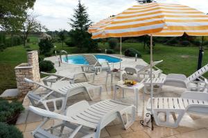 eine Gruppe Stühle und ein Sonnenschirm neben einem Pool in der Unterkunft Family friendly house with a swimming pool Guran, Central Istria - Sredisnja Istra - 7373 in Vodnjan