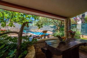 una veranda riparata con tavolo e piscina di Family friendly apartments with a swimming pool Krnica, Marcana - 7357 a Krnica