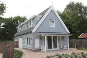una casa blanca con techo de gambrel en Lodge21Ouddorp, en Ouddorp