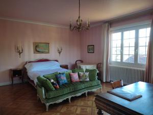 a bedroom with a bed and a green couch at ImaginaSoi in Dunières