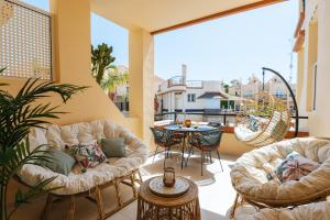 a patio with two couches and a table on a balcony at Amazing renovated pool view Apt, Aircon, 2 min to Fañabe Beach in Adeje