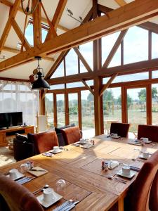 una gran mesa de madera en una habitación con ventanas en Chambres d'hôtes chez l'habitant - Bed& Breakfast homestay, en Huisnes-sur-Mer