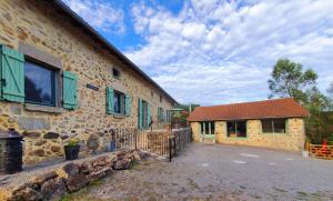 Casa de piedra con ventanas verdes y valla en La Porcherie en Saint-Mathieu