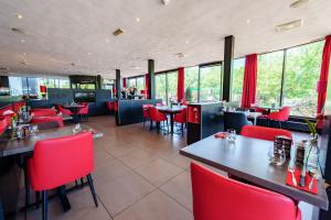 a restaurant with red chairs and tables and windows at Bastion Hotel Rotterdam Zuid in Rotterdam