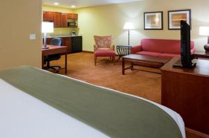 a hotel room with a bed and a living room at Holiday Inn Express Hotel and Suites Stevens Point, an IHG Hotel in Stevens Point