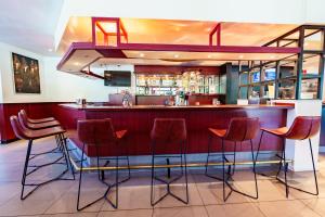 een bar in een restaurant met rode barkrukken bij Bastion Hotel Rotterdam Zuid in Rotterdam