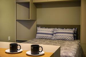 two coffee mugs on a table in a bedroom at NOVOS apartamentos STUDIO do ladinho do Paraguai in Foz do Iguaçu