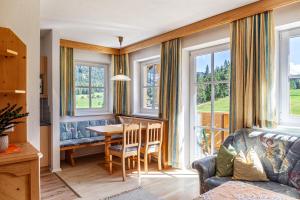 a living room with a table and a couch and windows at Landhaus Sonja 1 in Leutasch