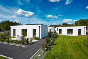 een groot wit huis met een tuin bij Village by logis in Le Gâvre