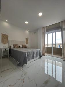a white bedroom with a bed and a large window at Apartamento Casa Blanca in Las Palmas de Gran Canaria