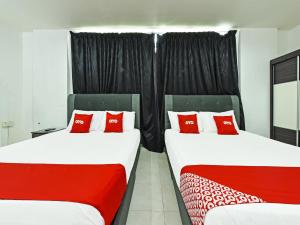 2 łóżka z czerwonymi poduszkami w pokoju w obiekcie Super OYO 90364 Hotel Gemilang w mieście Kuala Terengganu
