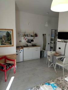 ポッツオーリにあるNew Flat in the Heart of Pozzuoliの白いキャビネット、テーブルと椅子付きのキッチンが備わります。