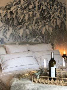 a bed with two glasses and wine bottles on a table at CARLIN Ferme Haute Prairie in Lourmarin