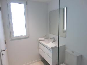 Baño blanco con lavabo y espejo en Total Valencia Torres de Quart, en Valencia