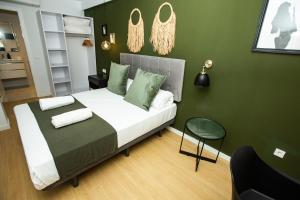 ein Schlafzimmer mit einem Bett mit grünen Wänden und einem Stuhl in der Unterkunft Total Valencia Torres de Quart in Valencia