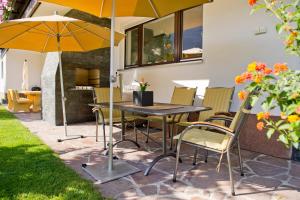 a patio with a table and chairs and an umbrella at Chalet H Montafon in Gaschurn