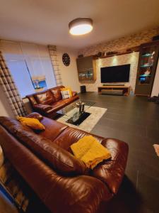 a living room with a leather couch and a television at Haus Moor Merland in Moormerland