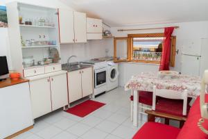 cocina con armarios blancos, mesa y fregadero en Casa Secci, en Santa Maria Navarrese