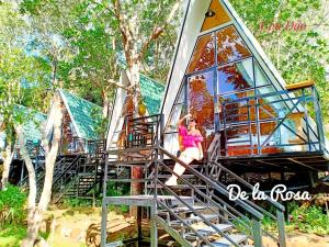 a woman sitting on the stairs of a tree house at Homestay De la Rosa - Côn Đảo in Con Dao