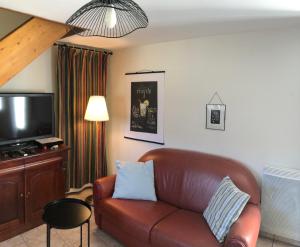 sala de estar con sofá de cuero marrón y TV en Normandia Parfum de pommes et d'histoire, en Nonant