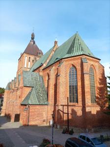 a large red brick church with a green roof at Przy Katedrze in Koszalin