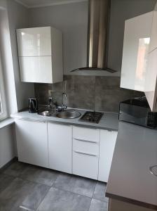 a kitchen with white cabinets and a sink at Przy Katedrze in Koszalin