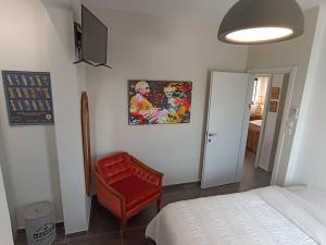 1 dormitorio con 1 cama y 1 silla roja en Hoffman Executive Suites - Beachfront Nahariya, en Nahariyya