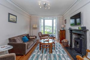 a living room with a couch and a table and a fireplace at Dolgellau Townhouse 2 Minutes to Town & Mountains in Dolgellau