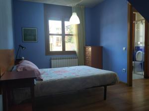 Dormitorio azul con cama y ventana en APARTAMENTO ARCE I en el Valle de Benasque, en Castejón de Sos