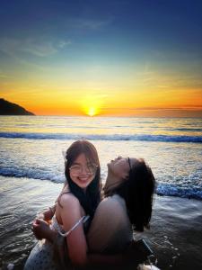 two women are hugging on the beach at sunset at Homestay De la Rosa - Côn Đảo in Con Dao