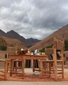une table et des chaises en bois avec des montagnes en arrière-plan dans l'établissement Auberge lac d'ifni, à Aoulouz