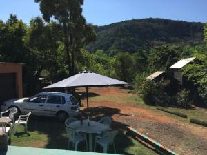 a table with an umbrella and chairs and a car at Sabie Gypsy's Backpackers in Sabie