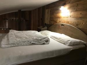 a bed with white sheets and a wooden wall at Le paradis du Cervin Grand'Ourse in Breuil-Cervinia