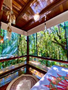 een kamer met een groot raam in een bos bij Housing 31 - Cond. Mata Azul - frente á entrada 18 in São Sebastião