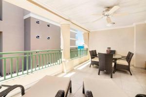 a balcony with a table and chairs and a ceiling fan at White Sands Beach Villas - Villas N- Lovely 1 Bed Condo in Christ Church