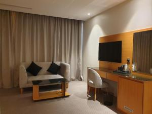 um quarto de hotel com uma cadeira e uma secretária com uma televisão em Al Rayyan Tower em Jeddah