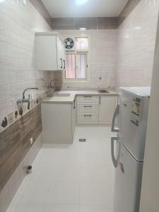 uma cozinha branca com um lavatório e um frigorífico em سجى للوحدات السكنية em Abha