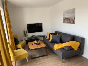 a living room with a gray couch and a table at eifel24, neues und modernes Appartement mit Dachterrasse in Schwirzheim