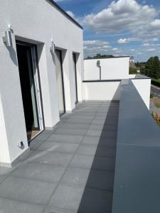 ein weißes Gebäude mit einem langen Gehweg in der Unterkunft eifel24, neu, modern mit Dachterrasse in Schwirzheim