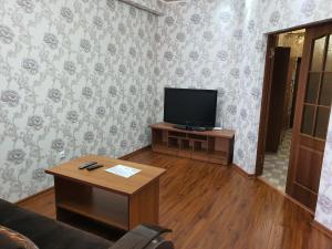 uma sala de estar com uma televisão e uma mesa de centro em Genny aparment in the center city em Bishkek