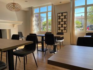 a dining room with tables and chairs and windows at Hôtel de la Glane in Oradour-sur-Glane