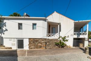 a white house with a stone wall at Casa das Rosas - Roses House in Miranda do Corvo