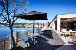 a patio area with a boat dock and a balcony overlooking the water at Nightcap at Waterfront Hotel in Maroochydore