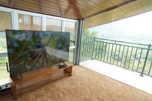 a large flat screen tv in a room with a balcony at Cinnamon Serenity Villa in Badulla