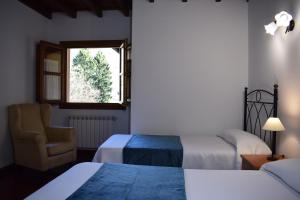 a room with two beds and a chair and a window at Apartamentos Rurales la Taberna in Matienzo