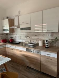 uma cozinha com armários brancos e um lavatório em Arvisura Vendégházak family friendly transit apartments em Zsombó