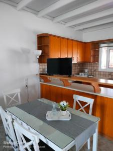 a kitchen with a table and chairs and a tv at Katakolo 180ο Sea View house near Ancient Olympia in Katakolon