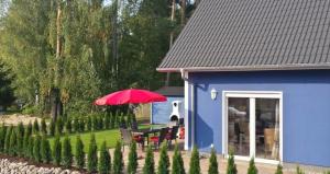 a blue house with a table and a red umbrella at Ferienhaus Strandräuber in Marienfelde